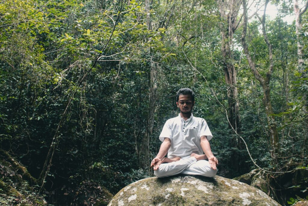 man in white polo shirt sitting on rock