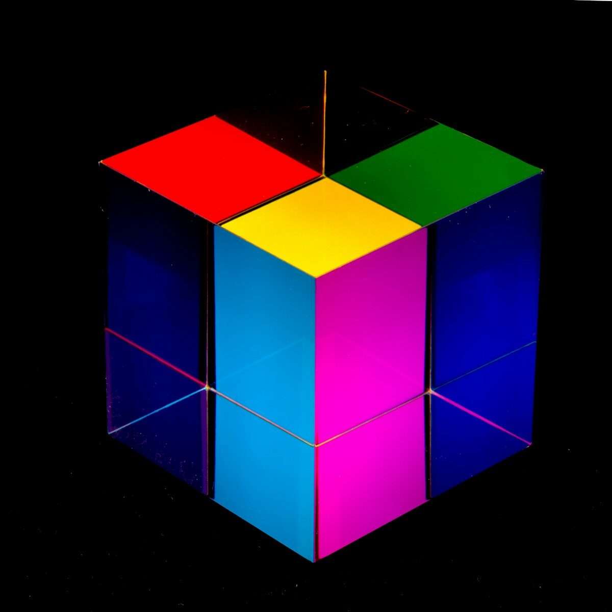Photo by Daniele Levis Pelusi a multicolored cube sitting on top of a black surface